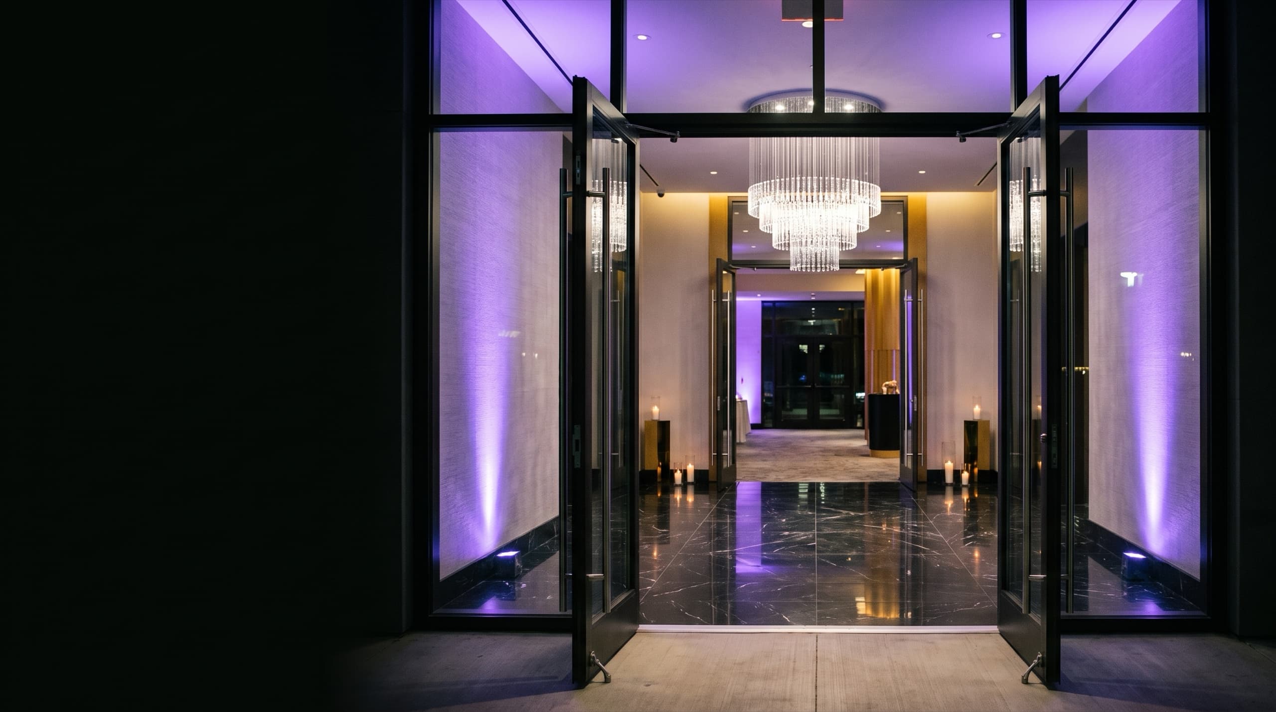 The entrance of an event venue at night, doors open and lights on